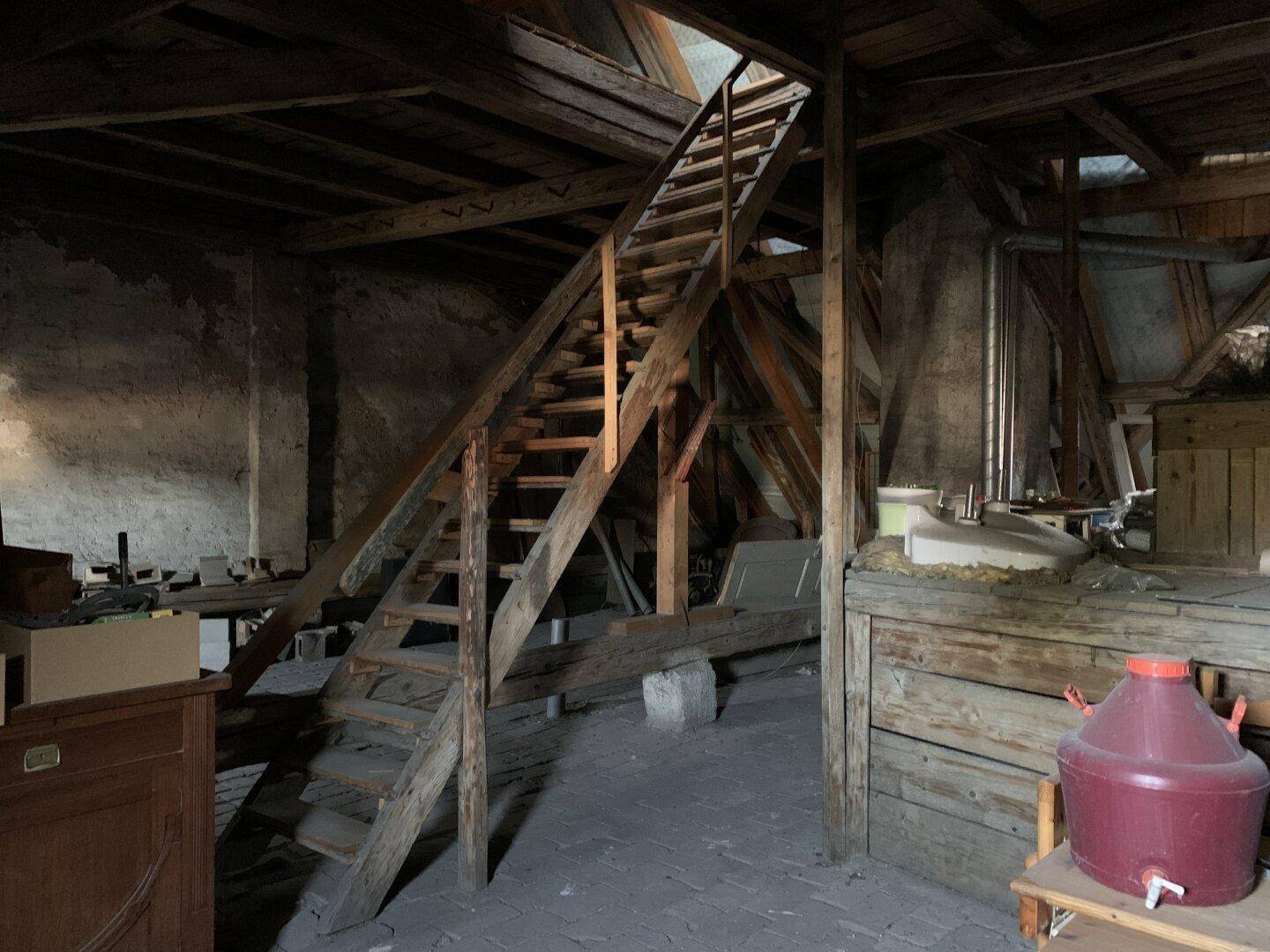 Großer Dachboden mit sichtbaren Holzbalken und einer Holztreppe, ideal für zukünftige Nutzung.