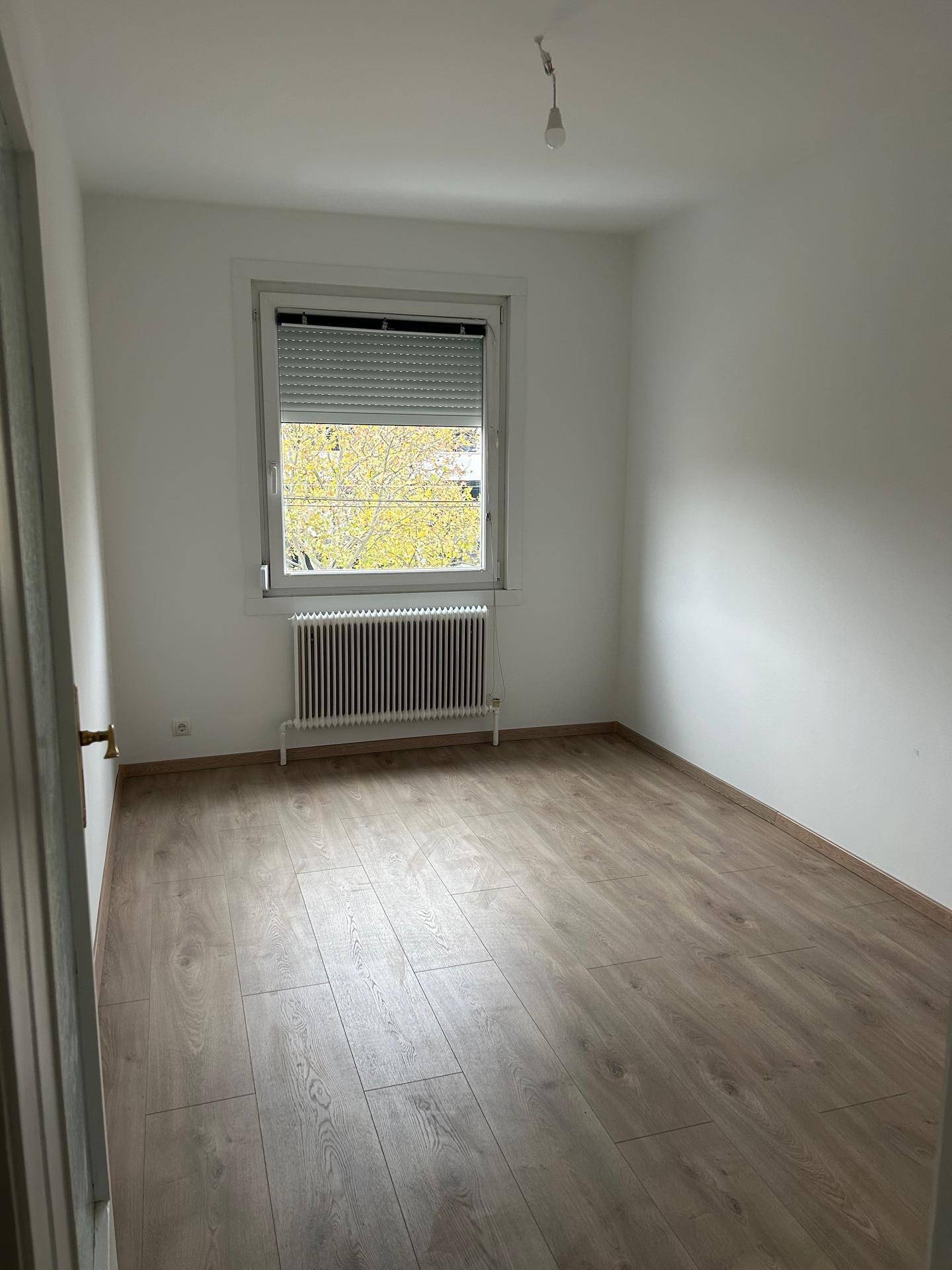 Gemütliches Zimmer mit Laminatboden, einem Fenster mit Rollladen und Heizkörper.