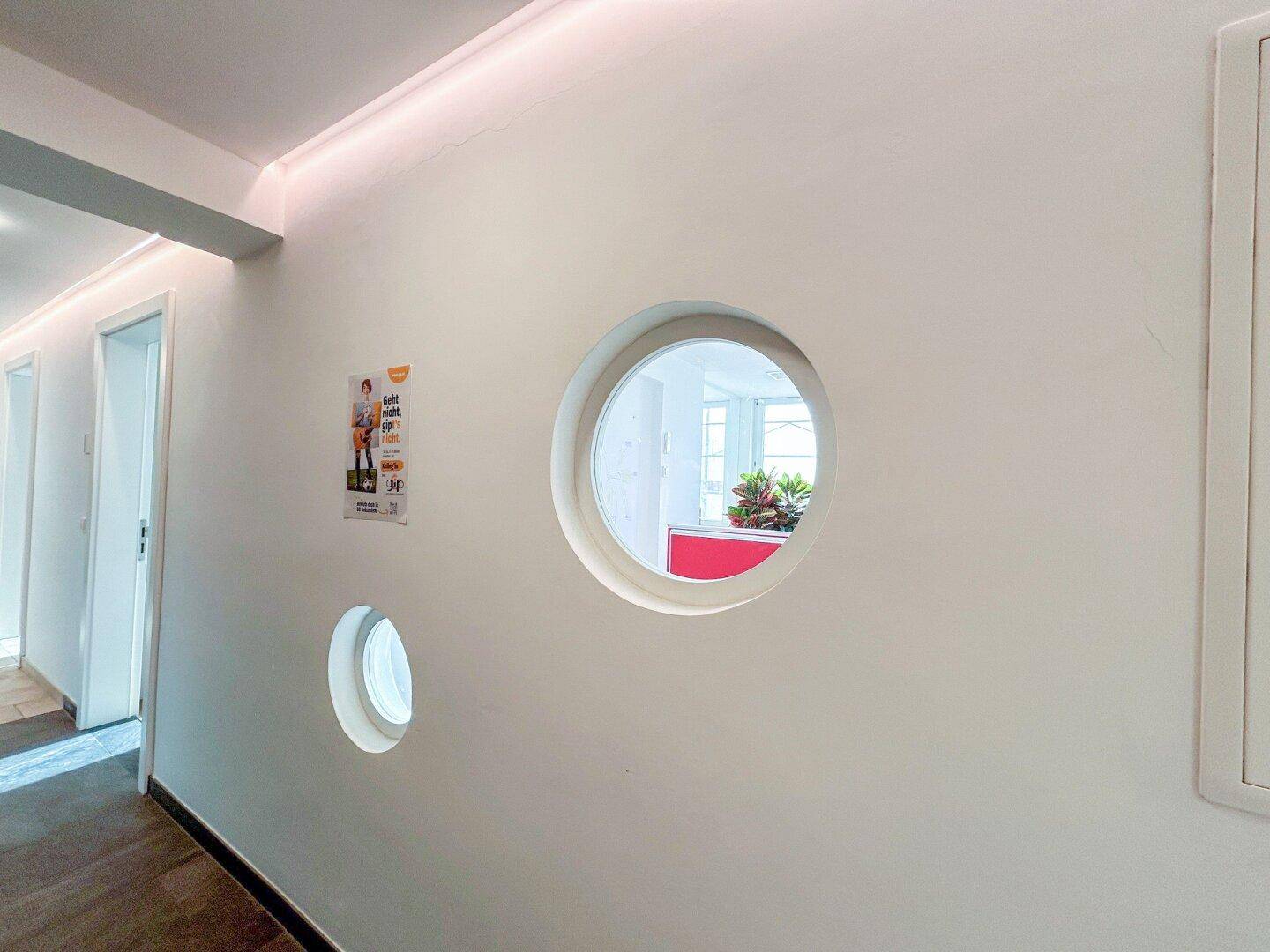 Flur mit runden Fenstern in der Wand, die Licht in den Raum lassen.