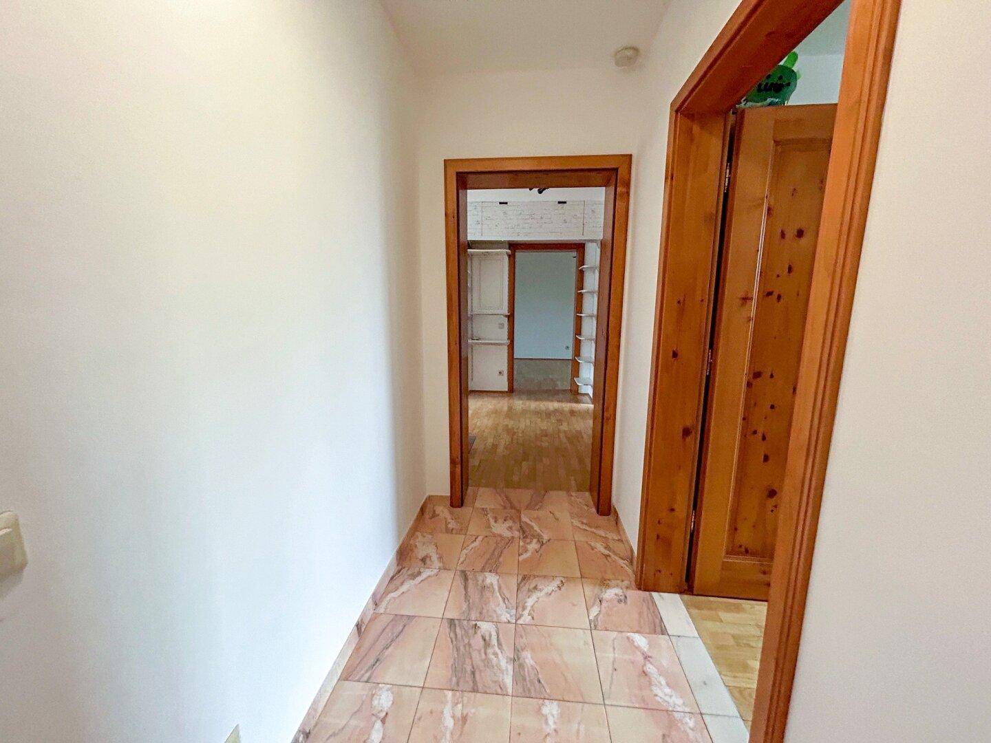 Heller Flur mit Fliesenboden, der verschiedene Räume der Wohnung miteinander verbindet.
