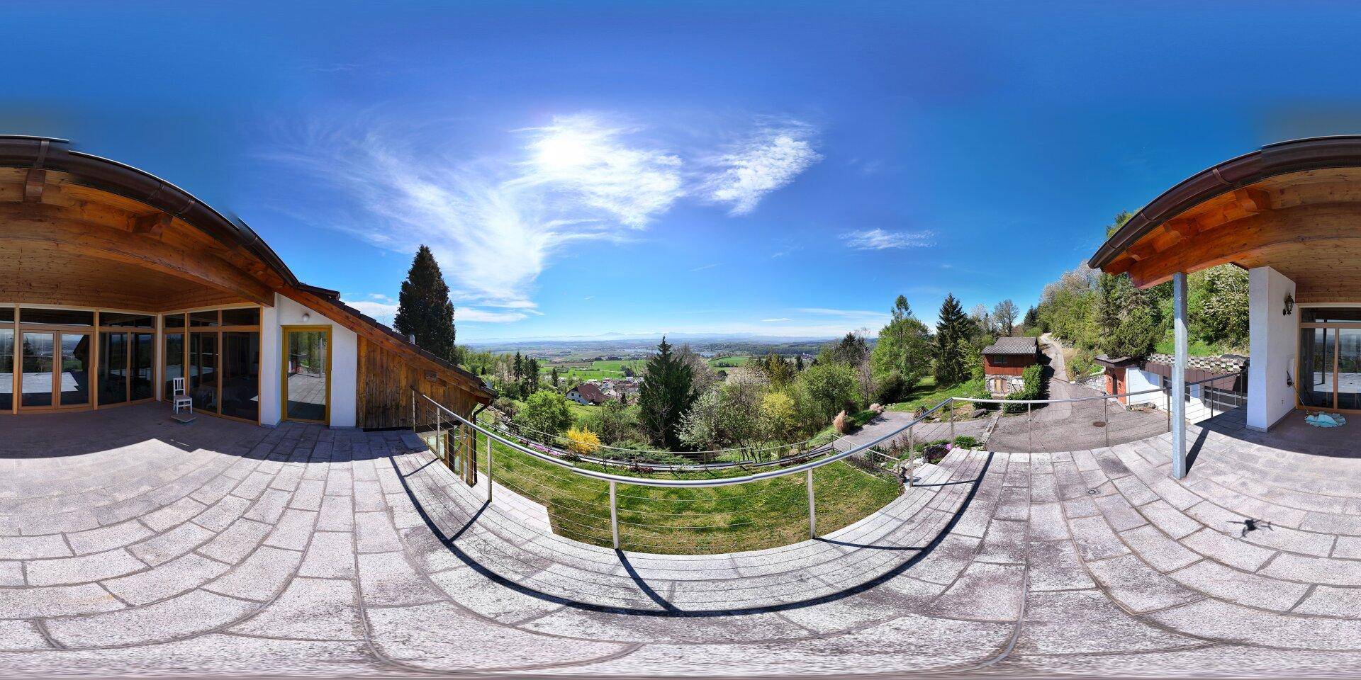 Weitläufige Terrasse mit Panoramablick auf die umliegende Natur und die Berge unter blauem Himmel.