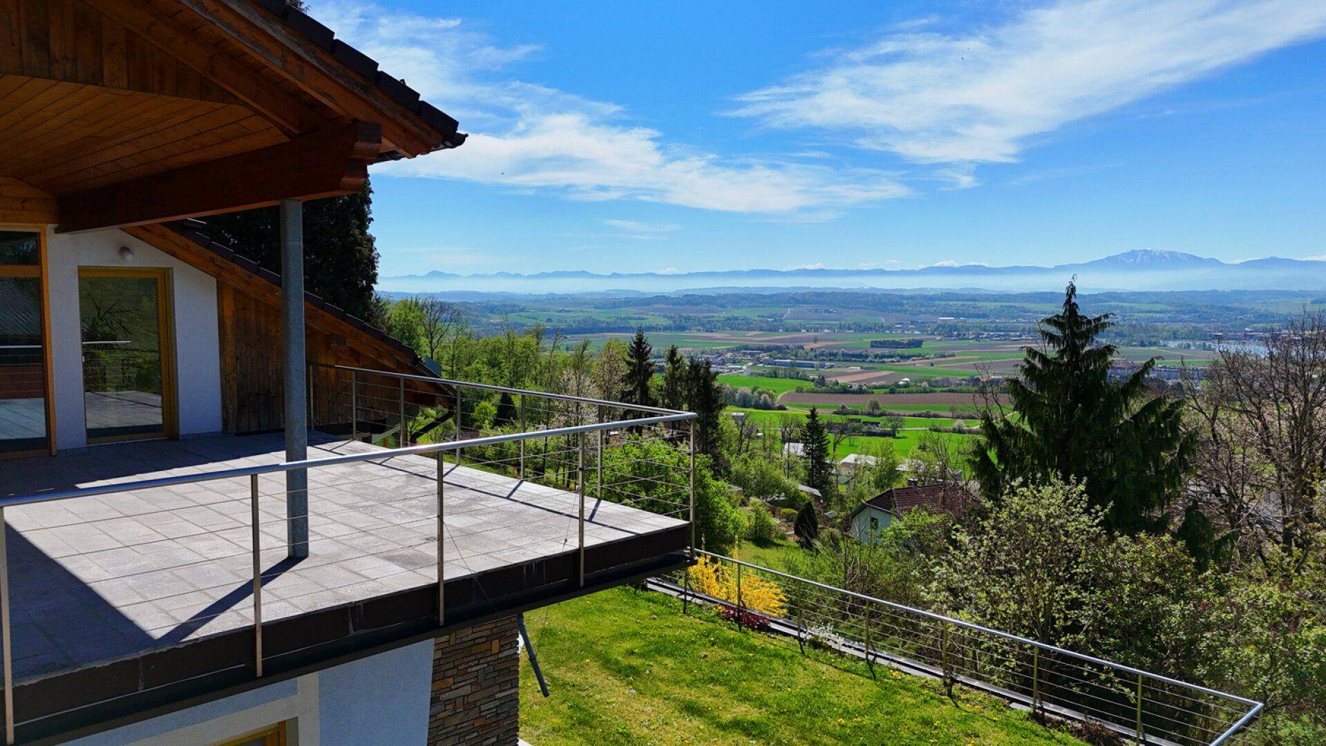 Geräumiger Balkon mit Fliesenboden und weitem Blick über die grüne Landschaft und Berge.