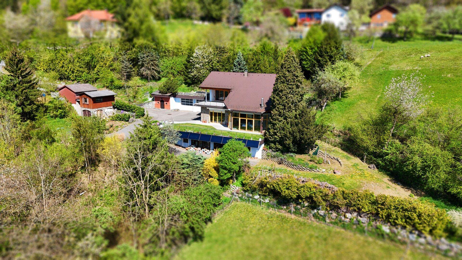Luftaufnahme des Anwesens mit Haupthaus, Nebengebäuden und weitläufiger grüner Umgebung.