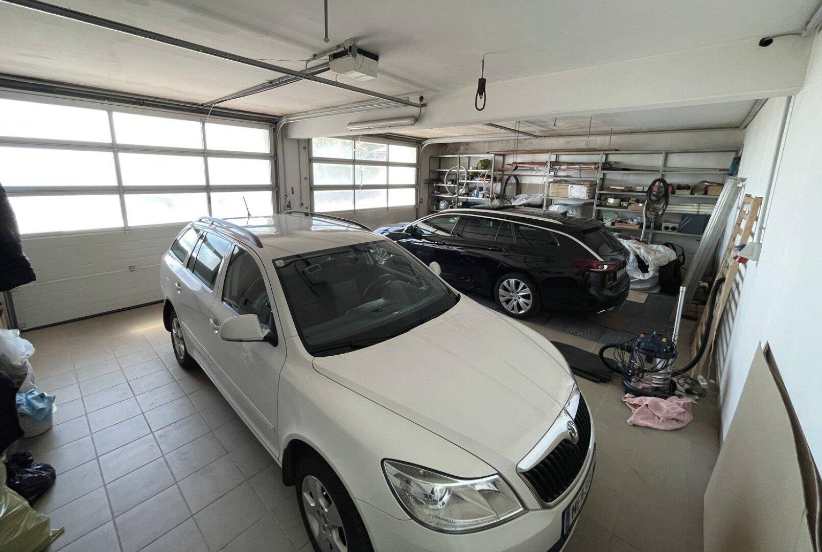 Geräumige Garage mit Fliesenboden und Platz für zwei Fahrzeuge, inklusive Stauraum.