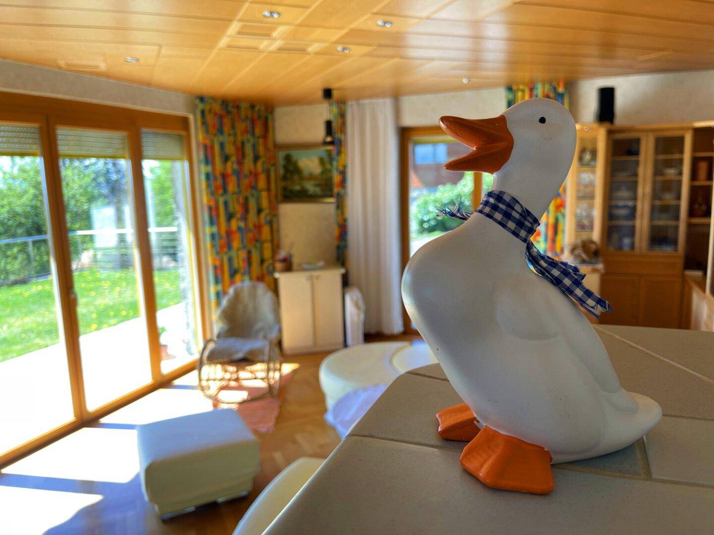 Wohnzimmer mit großen Fenstern, die einen weiten Blick ins Grüne bieten, und dekorativen Elementen.