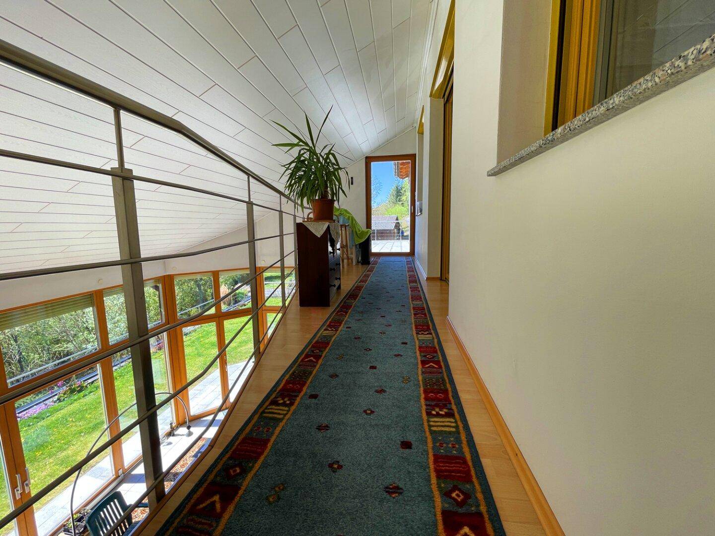 Heller Flur im Obergeschoss mit Teppichläufer und Blick auf die darunterliegende Etage.