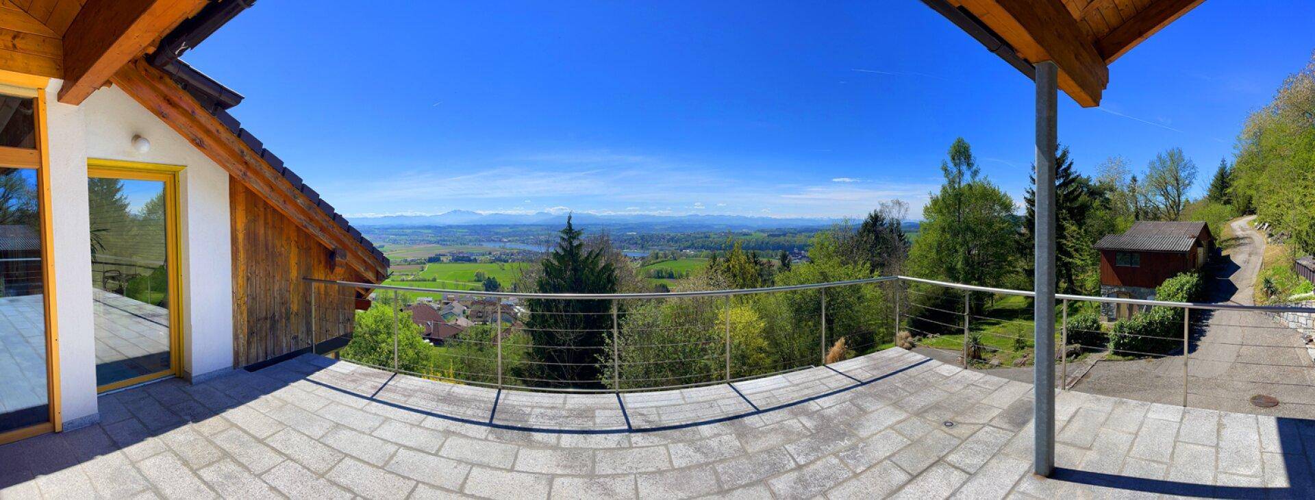 Panoramablick von der Terrasse über die weite Landschaft und die umliegenden Berge.