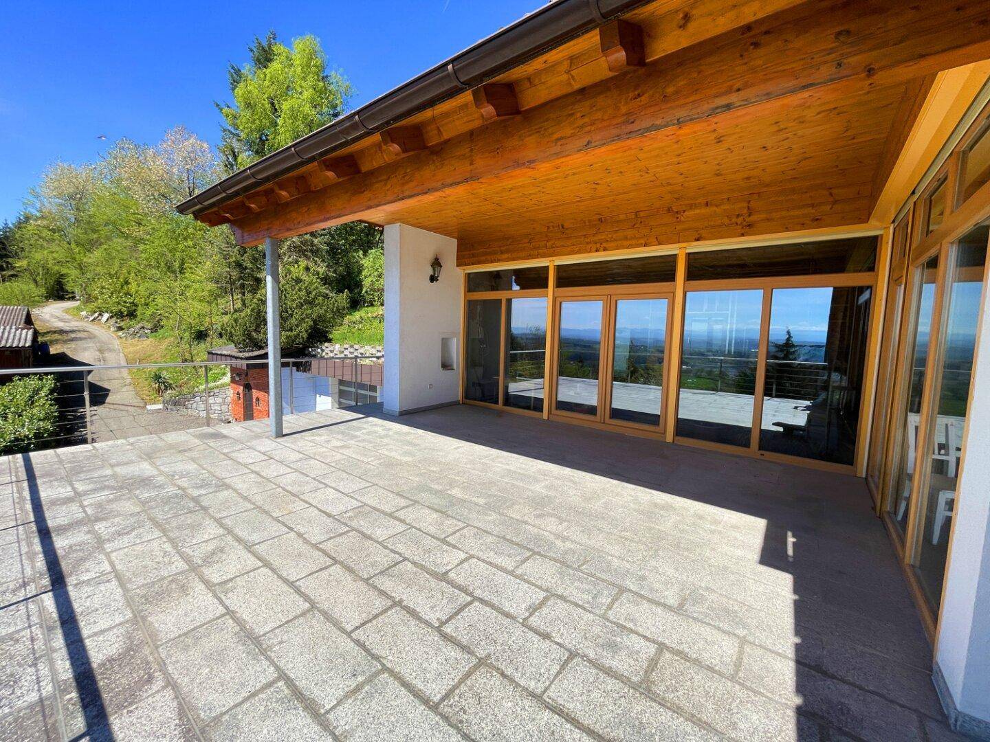 Geräumige Terrasse mit Steinplatten und Holzdach, ideal für Entspannung mit Fernblick.