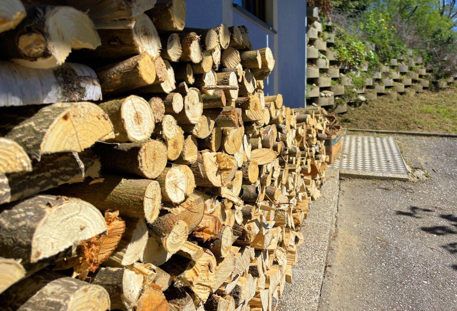 Ordentlich gestapeltes Brennholz an der Hauswand, bereit für den Kamin oder Ofen.