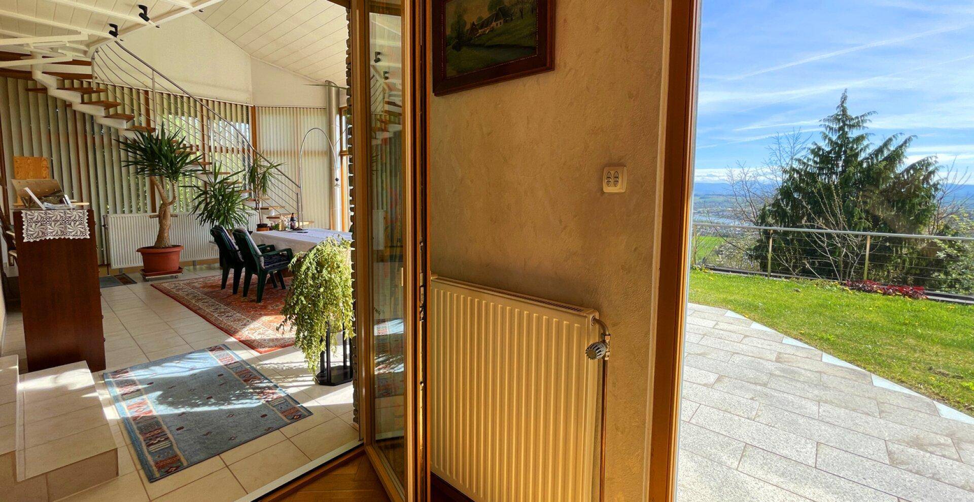 Heller Wintergarten mit Zugang zur Terrasse und weitem Blick in die Natur.