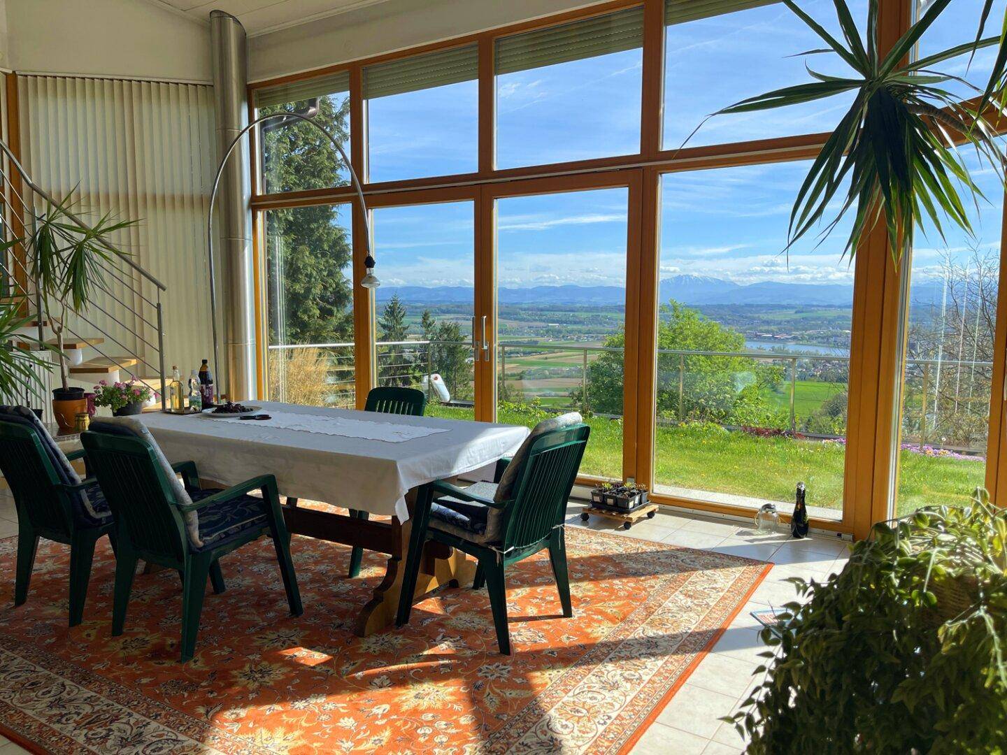 Helles Esszimmer mit großen Fensterfronten, die einen weiten Blick auf die Landschaft und die Berge bieten.