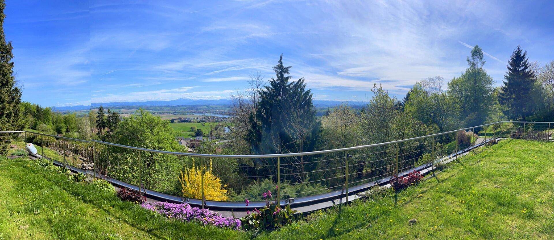 Weitläufiger Gartenbereich mit Panoramablick auf die grüne Landschaft und ferne Berge.