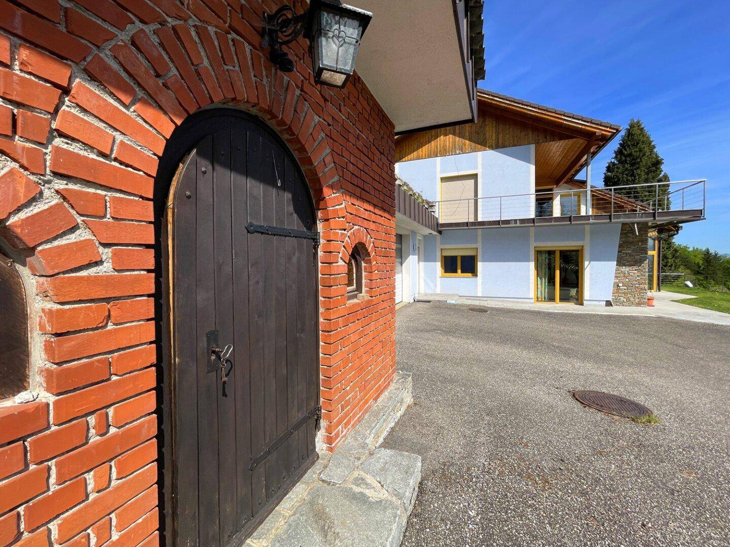 Traditioneller Eingangsbereich aus Ziegelstein mit Blick auf die moderne Gebäudefassade und den Vorplatz.