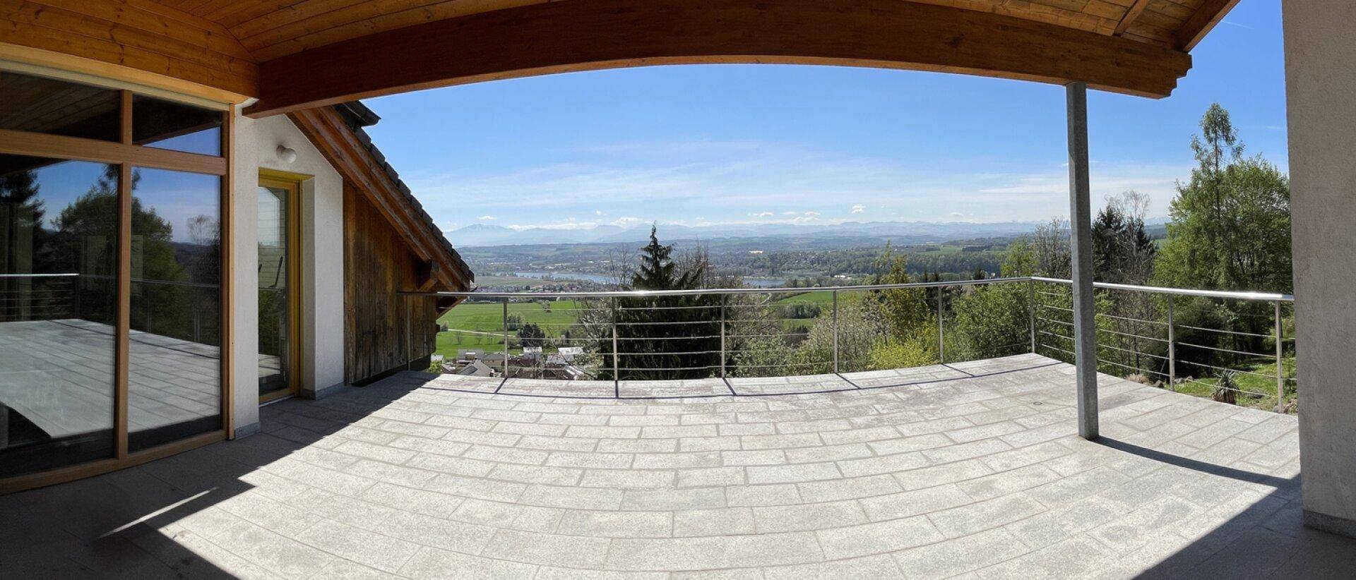 Große gepflasterte Terrasse mit weitem Blick über die Landschaft und die Alpen.