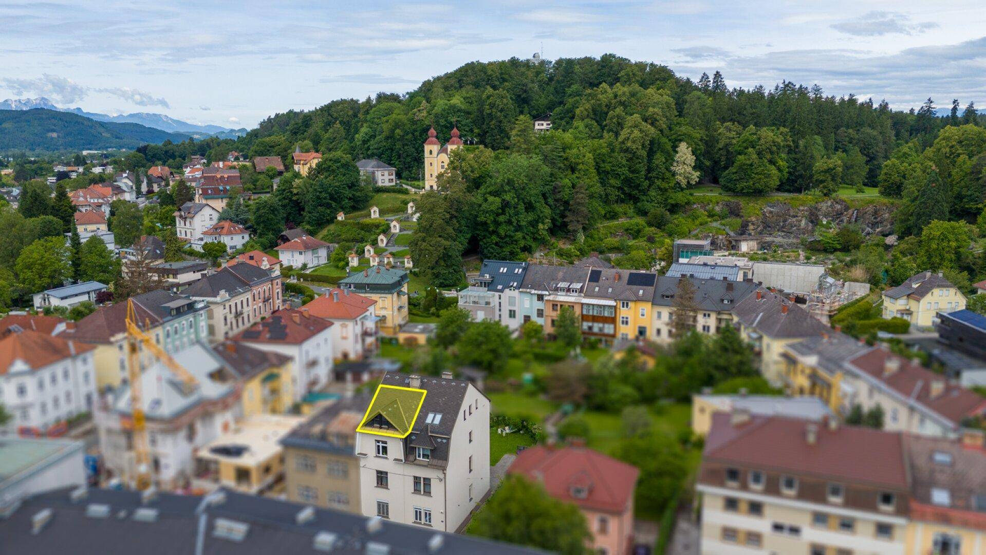 Luftaufnahme des Gebäudes in einer grünen Umgebung mit Blick auf die Stadt und Berge.