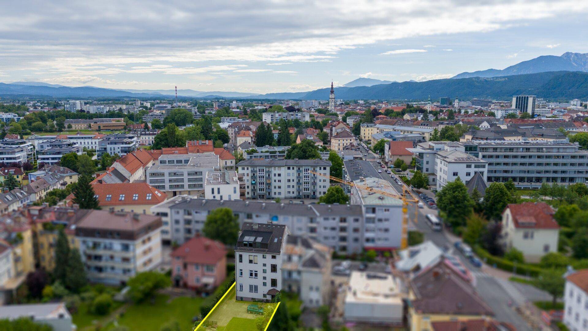 Weitläufige Luftaufnahme der Stadt mit dem Gebäude im Vordergrund und Bergpanorama.