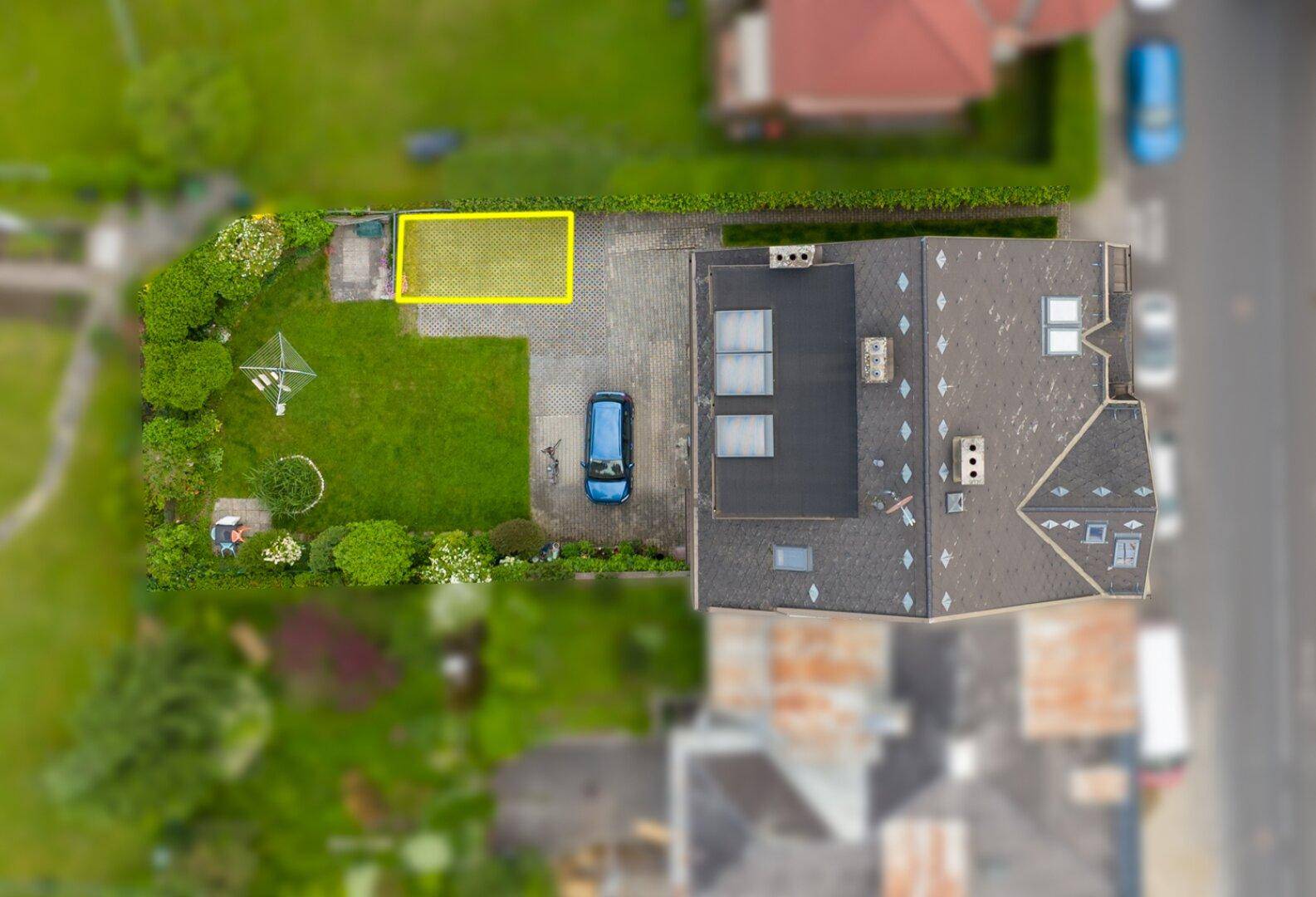 Draufsicht des Gebäudes mit Satteldach, Flachdachanteil, Einfahrt und Gartenbereich.