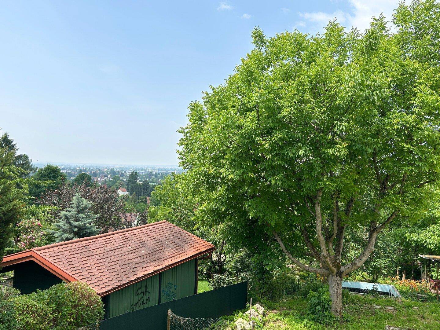 Malerischer Ausblick auf die grüne Landschaft und die Dächer der umliegenden Häuser.