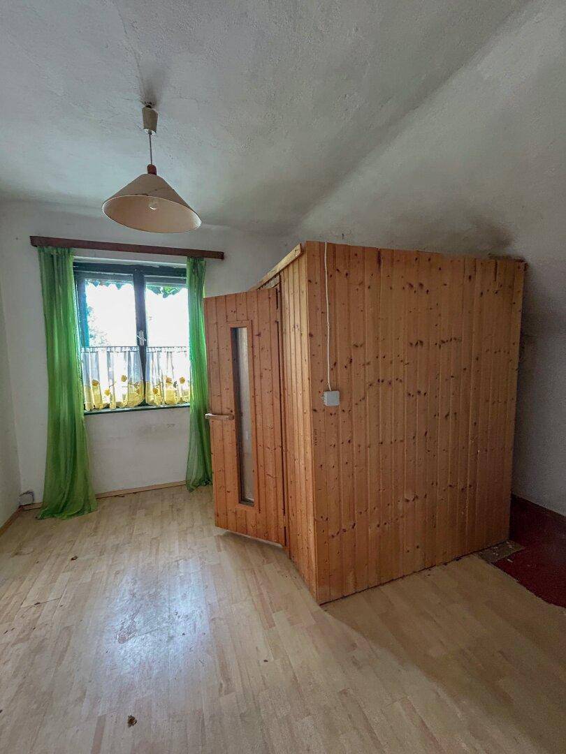 Schlafzimmer im Dachgeschoss mit Holzboden, Fenster und einer eingebauten Sauna.