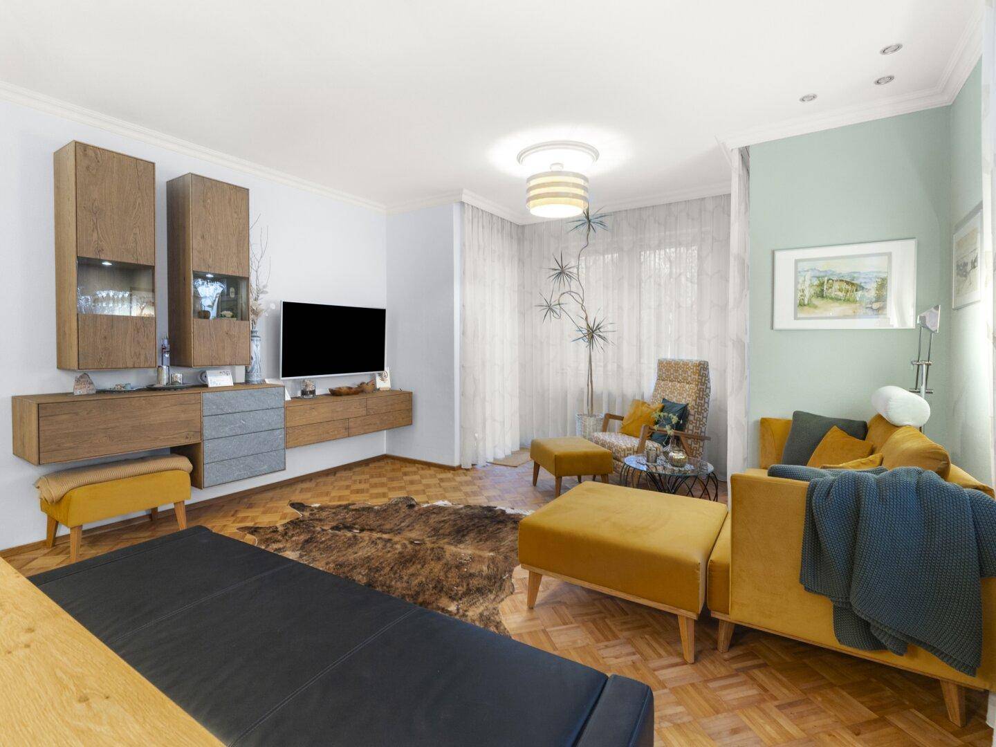 Gemütliches Wohnzimmer mit Parkettboden, modernen Möbeln und gelben Akzenten, gut beleuchtet.