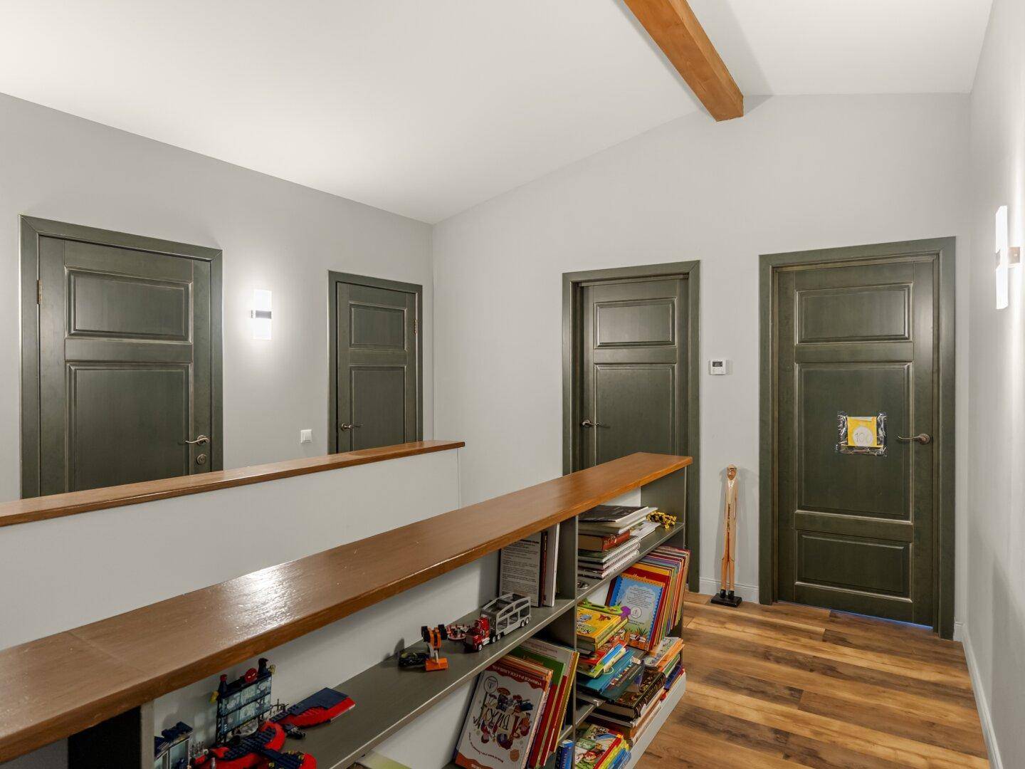 Heller Flur mit Holzboden, Bücherregal und mehreren Türen zu den Zimmern.