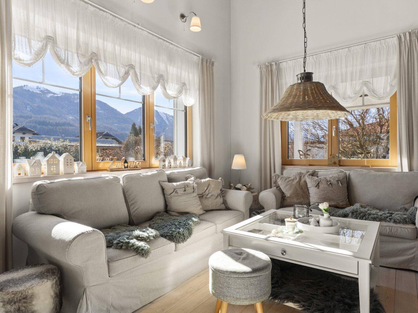 Gemütliches Wohnzimmer mit Bergblick, hellen Sofas und rustikalen Vorhängen für entspannte Stunden.