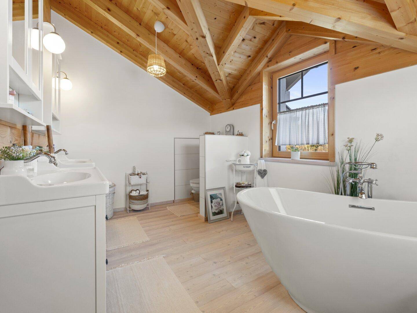 Modernes Badezimmer mit freistehender Badewanne, Doppelwaschbecken und Holzbalkendecke.