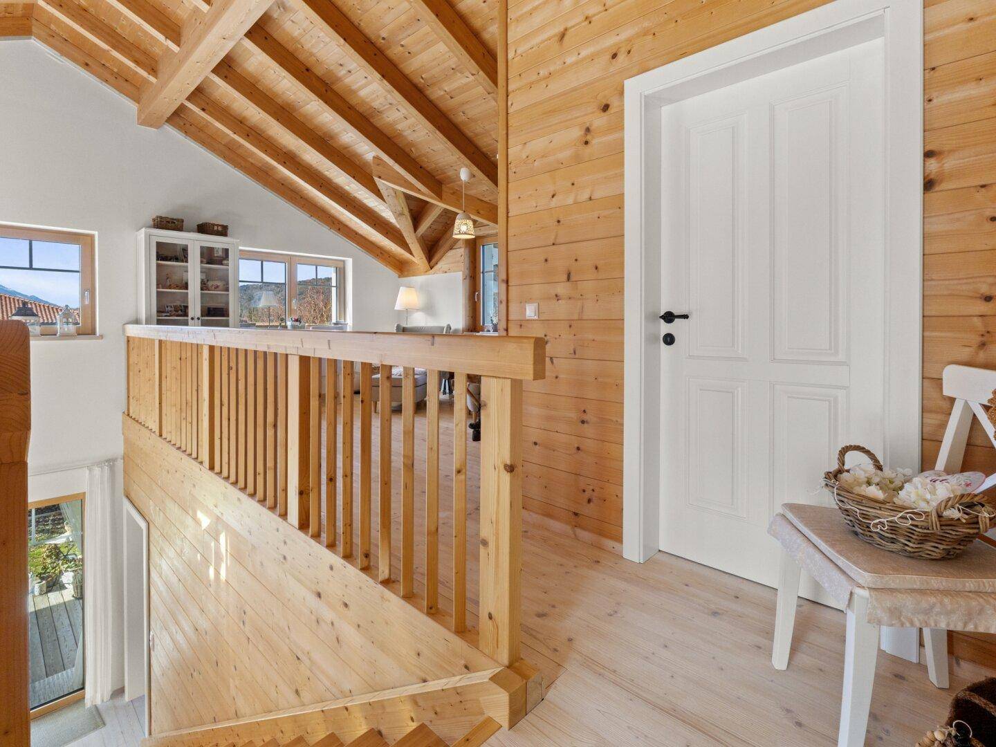 Heller Flur im Obergeschoss mit Holzgeländer und Blick auf die umliegende Landschaft.