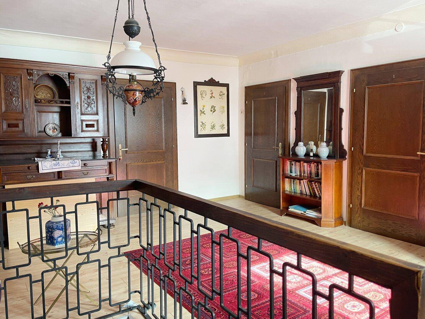 Geräumiger Flur mit traditionellen Holzmöbeln, Teppich und Zugang zu mehreren Zimmern im Obergeschoss.