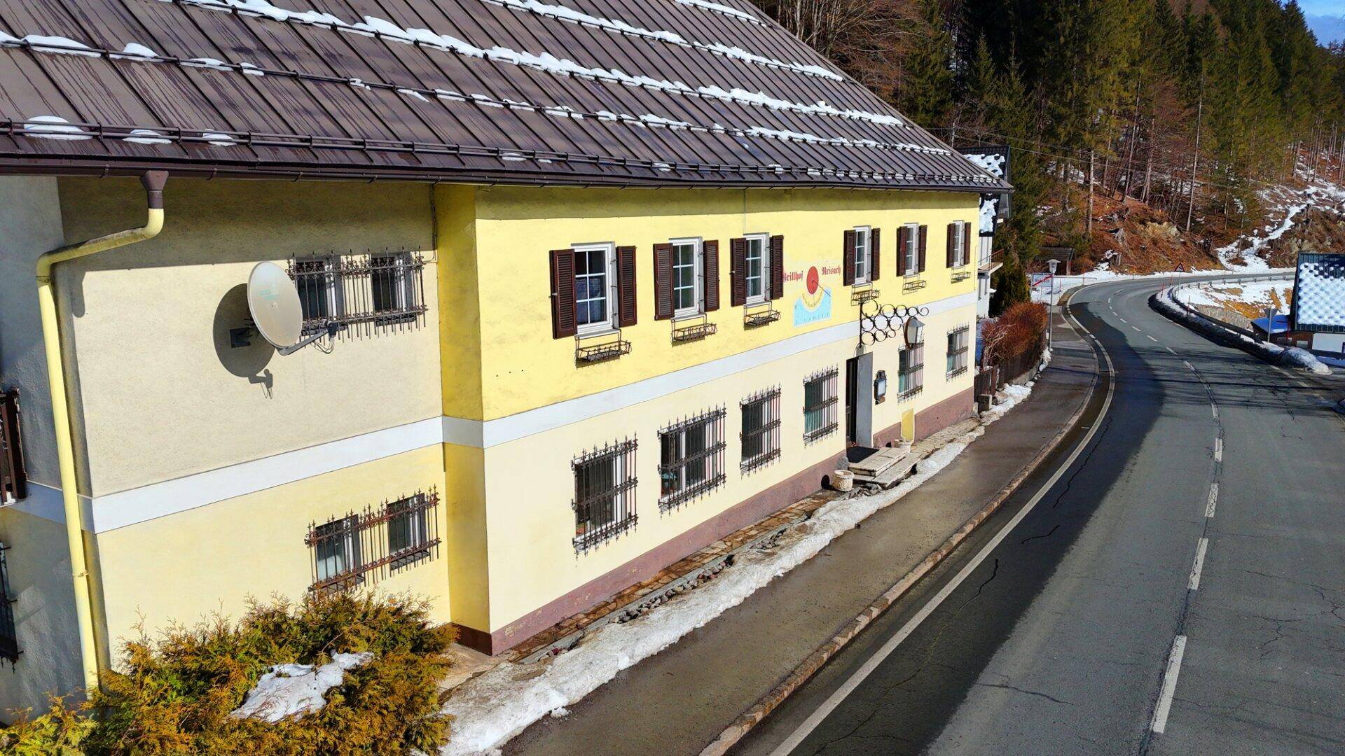 Luftaufnahme des Hauses im Winter mit schneebedecktem Dach und der umliegenden Straße in ländlicher Umgebung.