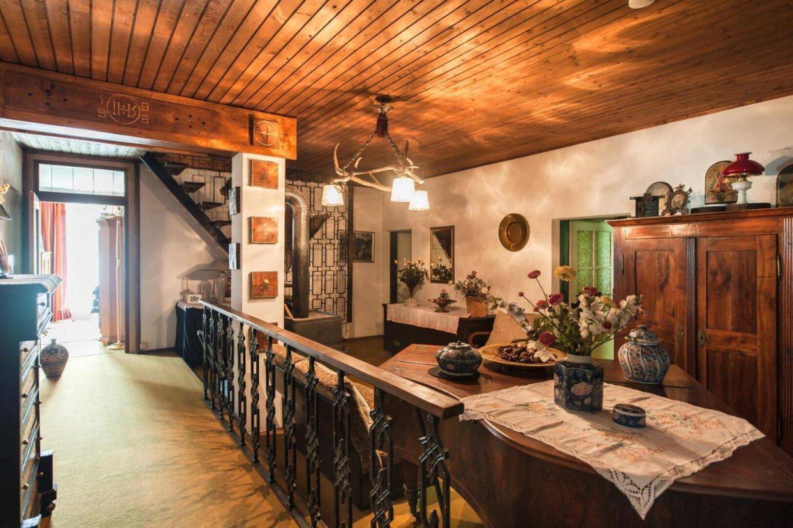 Rustikaler Innenbereich mit Holzbalkendecke, traditionellen Möbeln und einem Hirschgeweih-Kronleuchter.