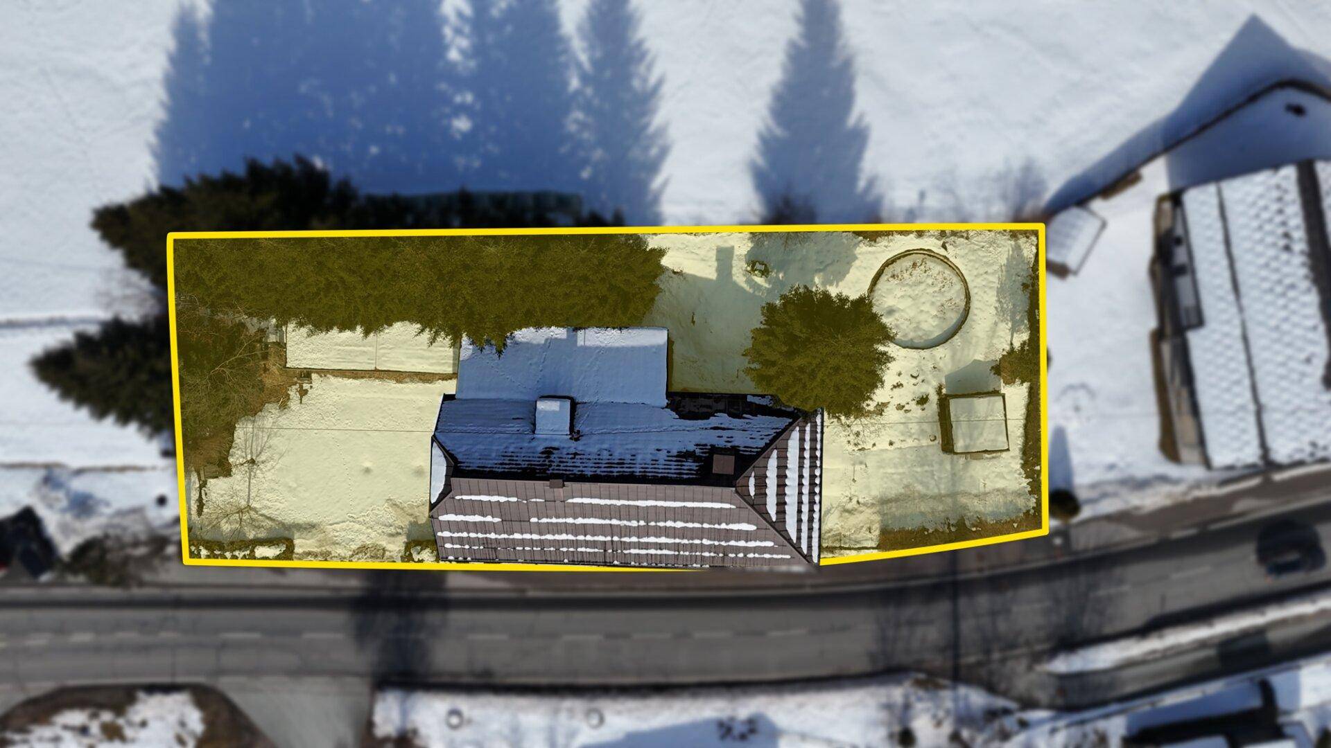 Draufsicht des Grundstücks mit gelber Umrandung, Haus und schneebedecktem Gartenbereich im Winter.
