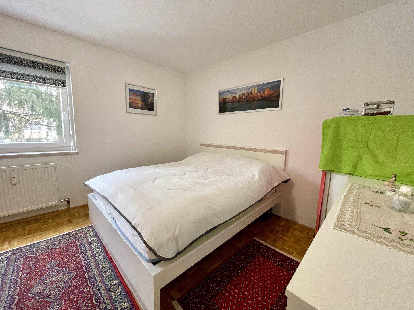 Gemütliches Schlafzimmer mit Doppelbett, Holzboden und Teppich, hell und einladend.