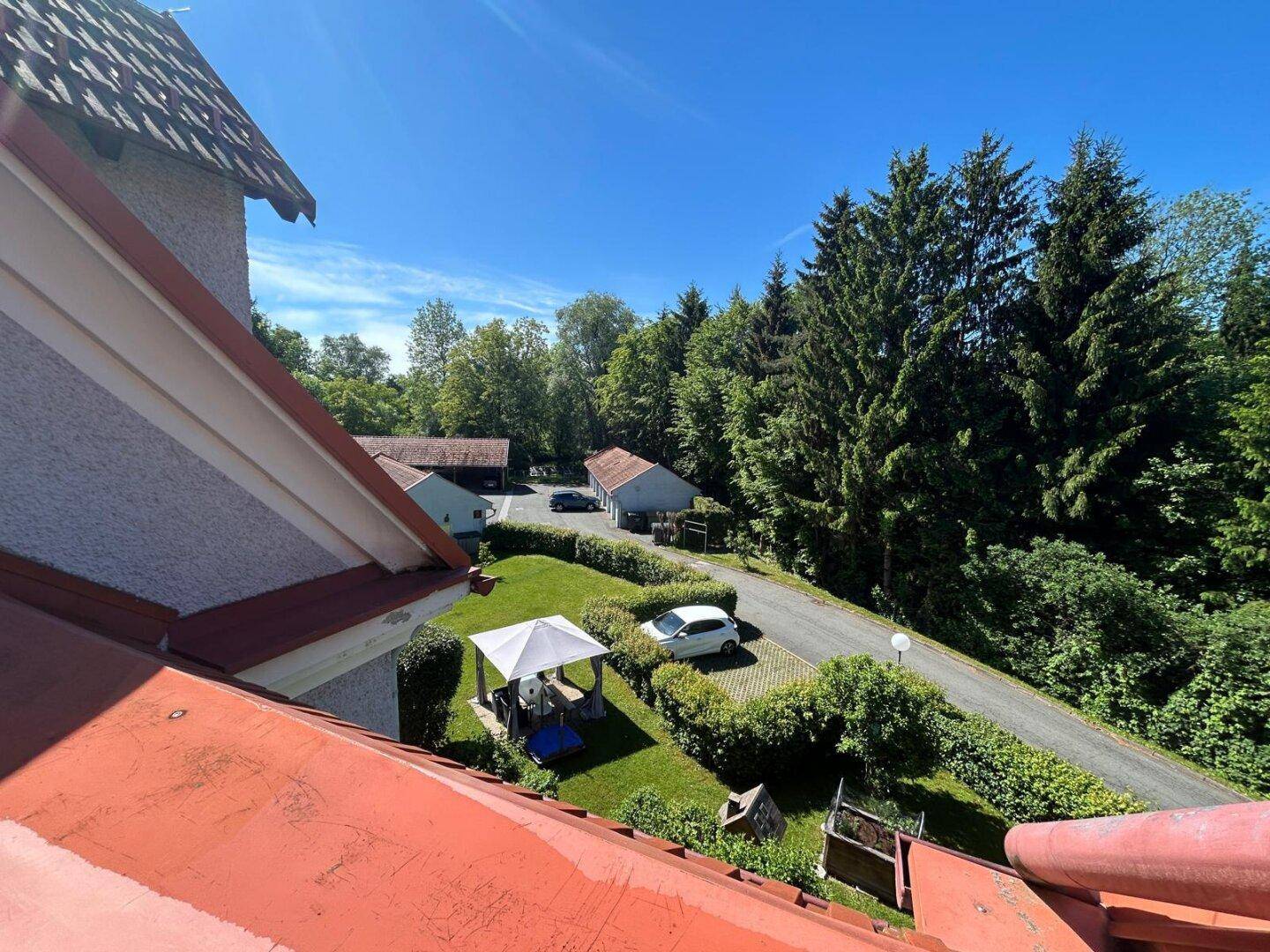 Panoramablick über die ländliche Umgebung mit Bäumen, Gärten und einem Pavillon.
