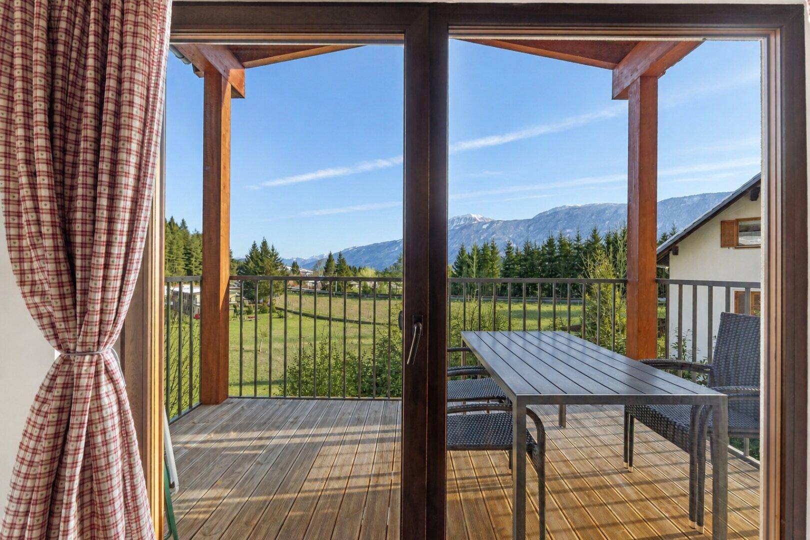 Balkon mit Holzboden und Sitzgelegenheiten, bietet einen weiten Blick auf die Berge und Natur.