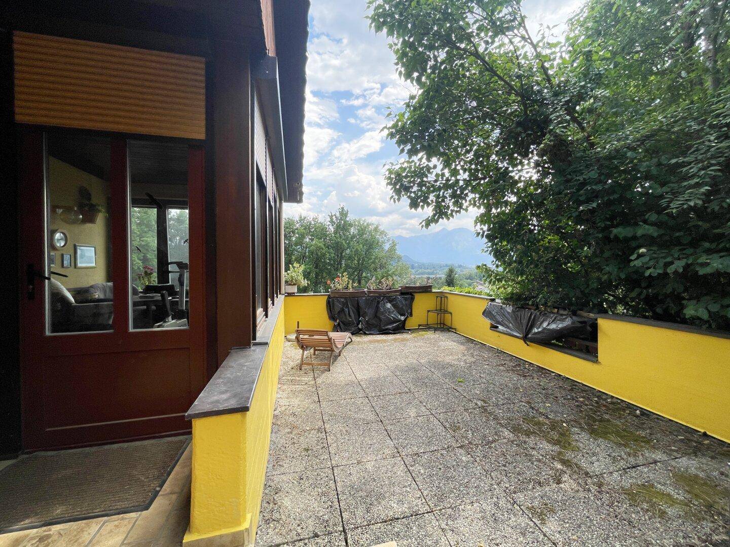Geräumige, geflieste Terrasse mit gelber Brüstung und Blick auf die umliegende Landschaft.