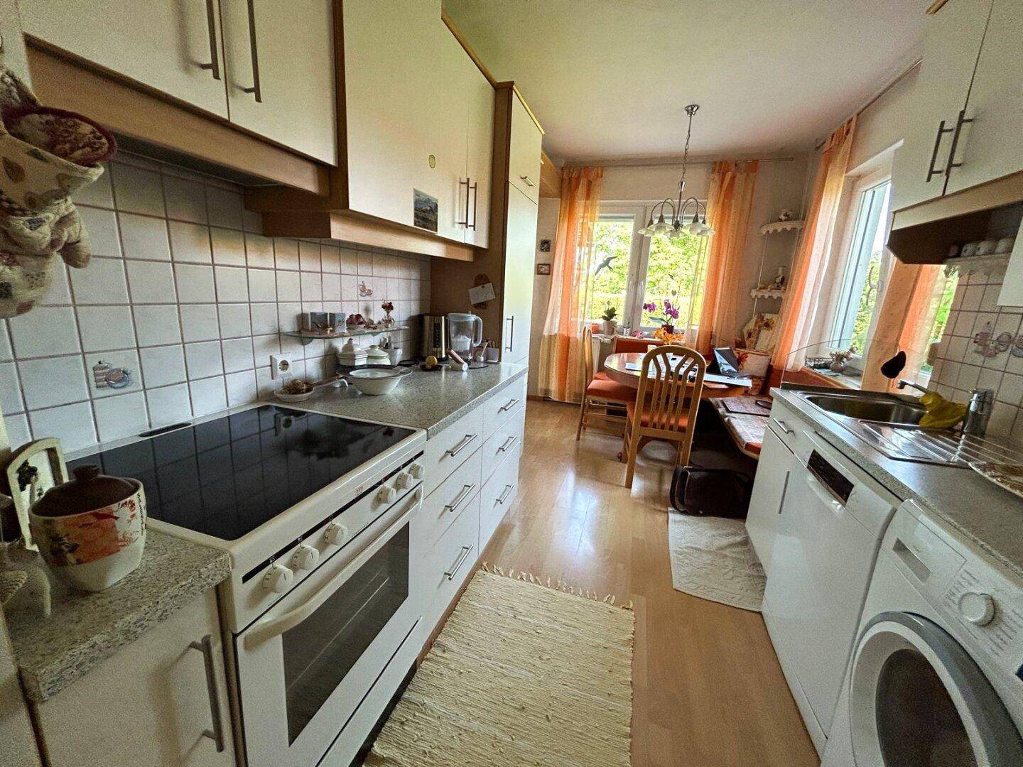 Funktionale Küche mit Einbaugeräten, Fliesenrückwand und kleinem Essbereich am Fenster.