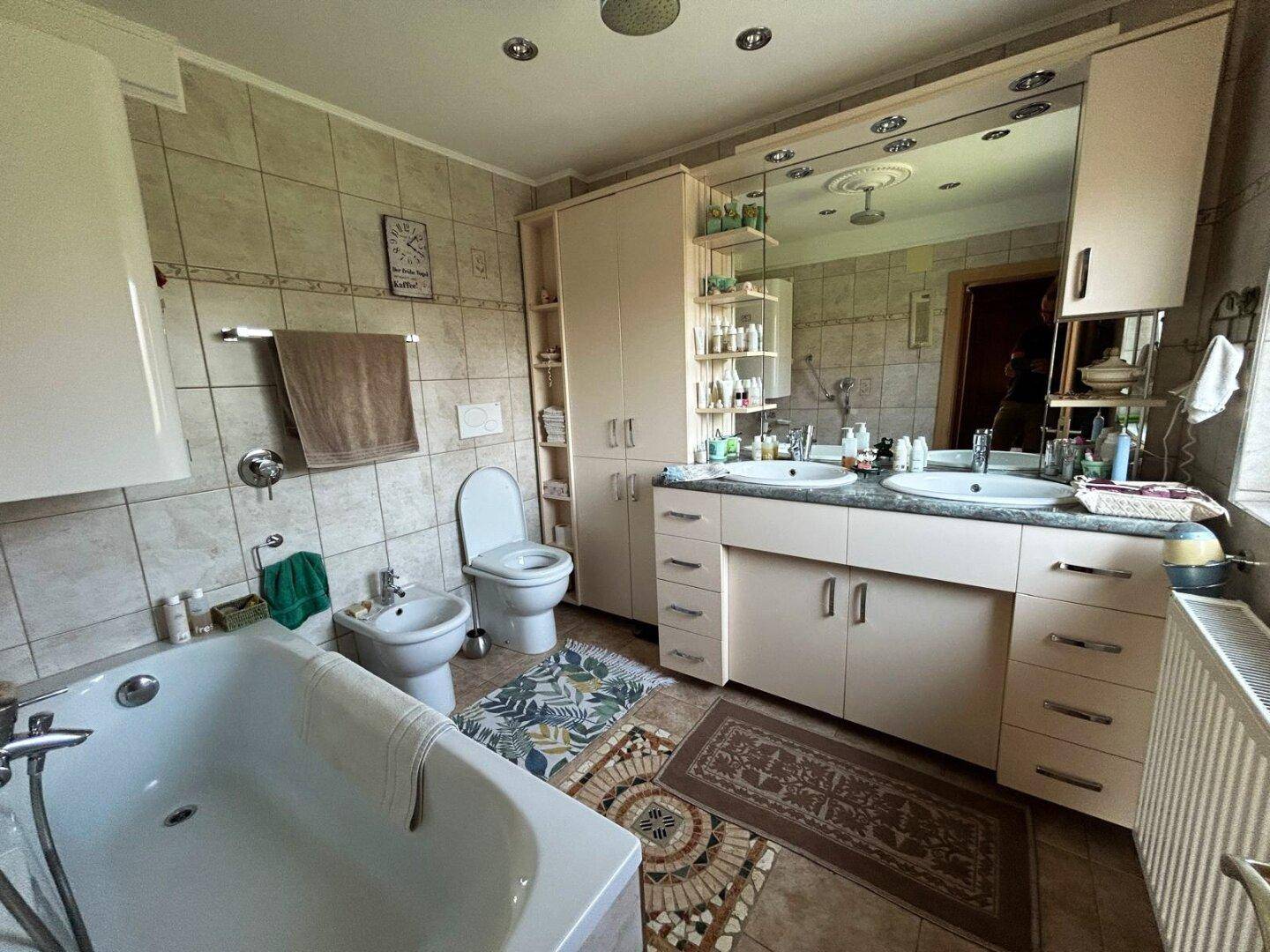 Geräumiges Badezimmer mit Badewanne, Bidet, Doppelwaschbecken und großem Spiegelschrank.