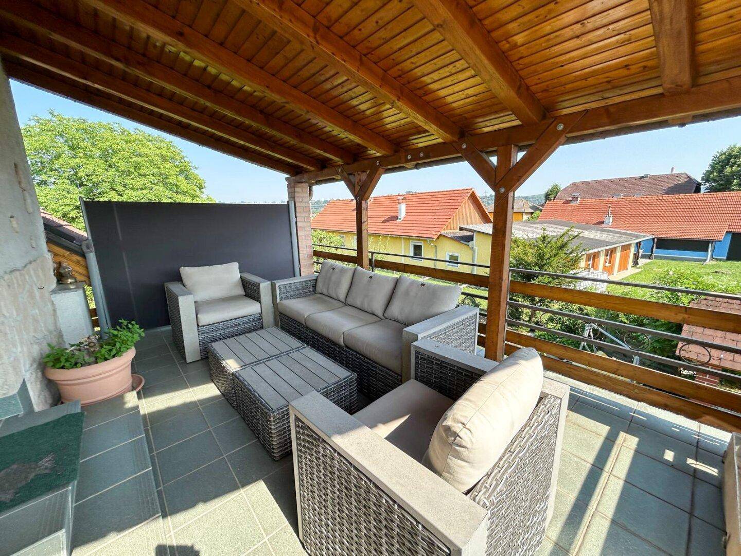 Überdachte Terrasse mit modernen Outdoor-Möbeln und Blick auf die Nachbarschaft.