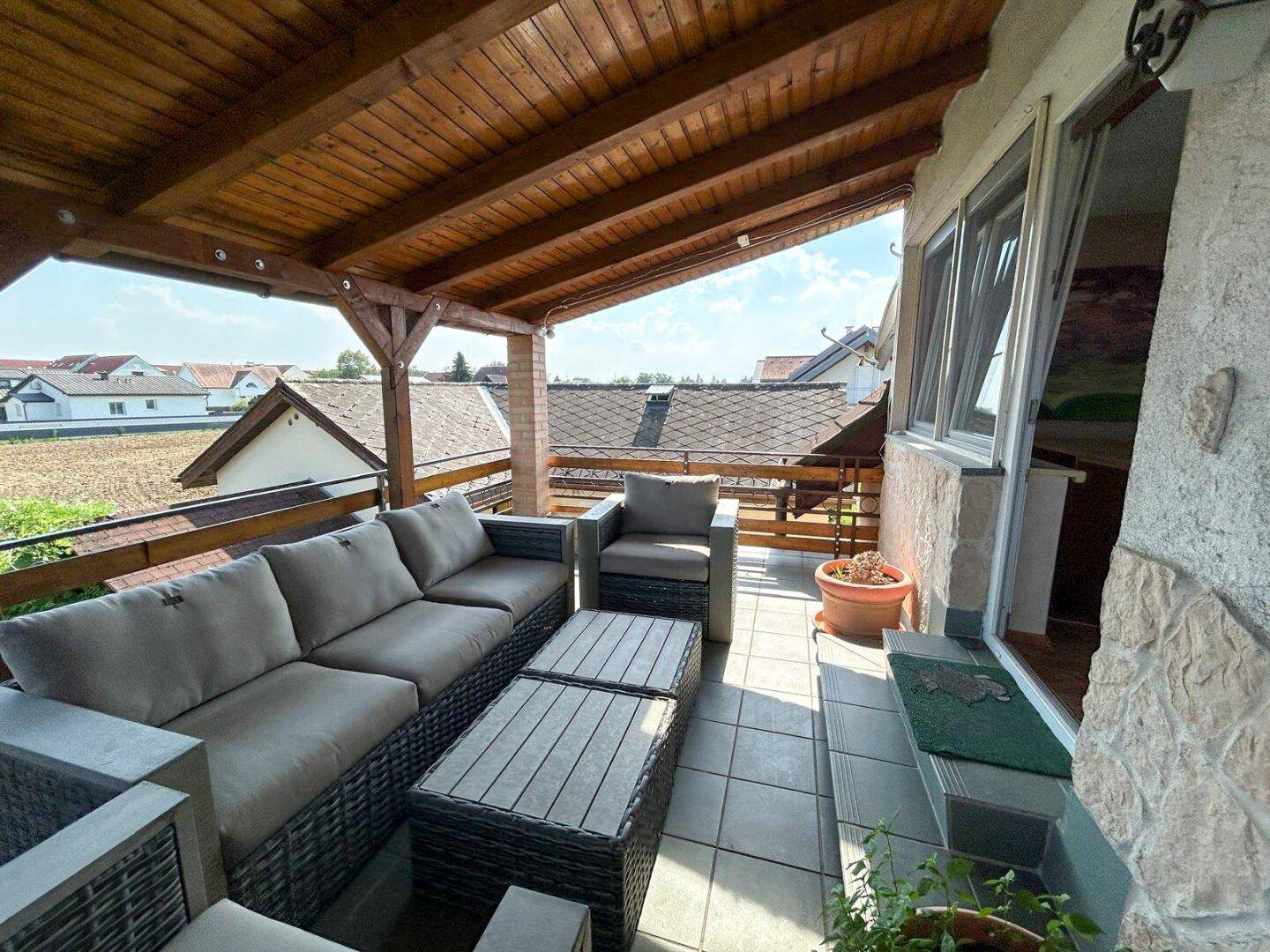 Geräumige überdachte Terrasse mit bequemen Loungemöbeln und weitem Blick.