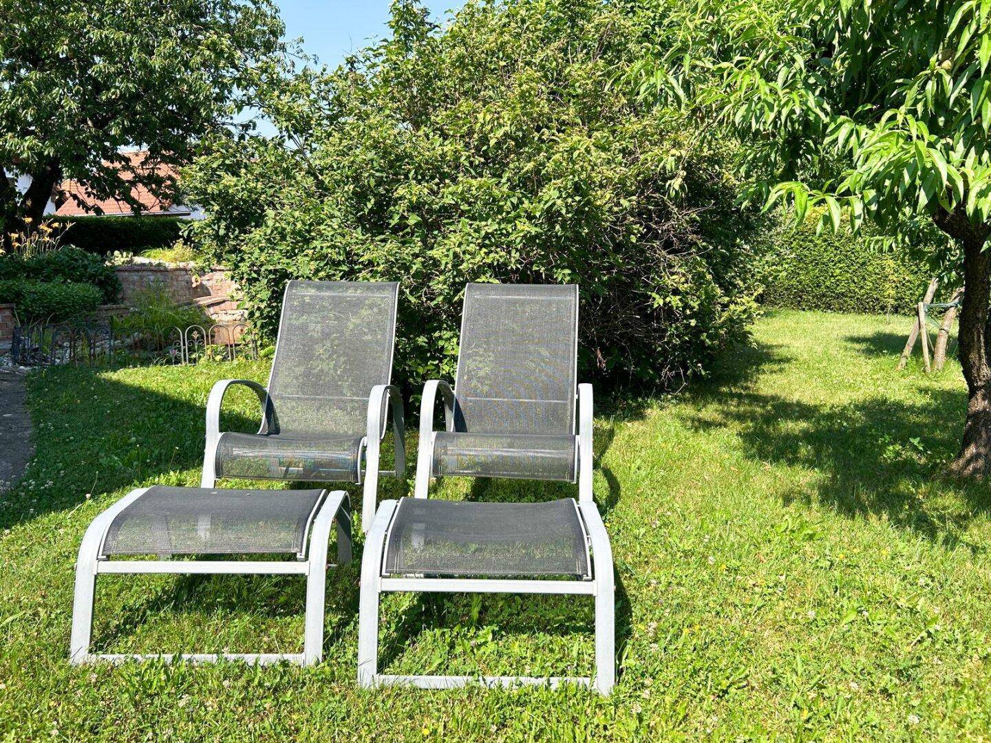 Entspannungsbereich im Garten mit zwei Liegestühlen auf der Rasenfläche.