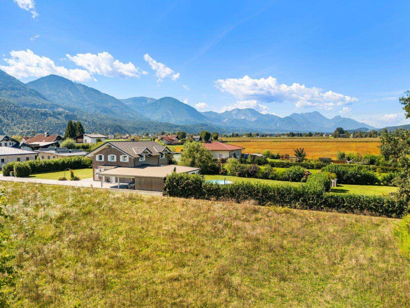 Weitläufige Landschaft mit Wohnhaus, Pool und majestätischem Bergblick.