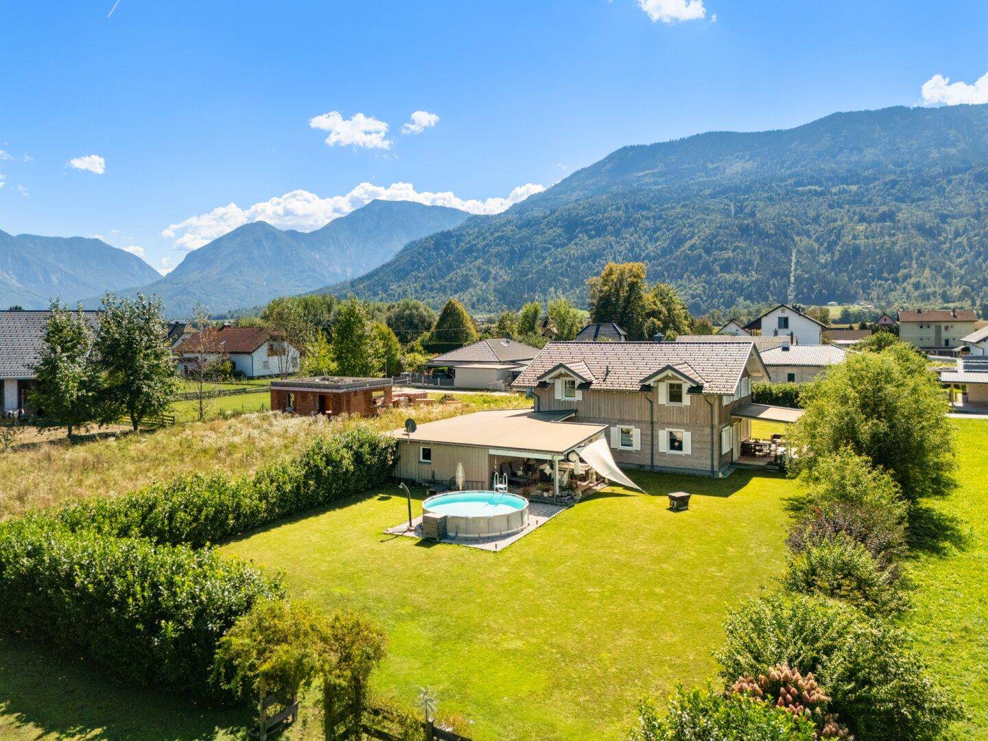 Luftaufnahme des Anwesens mit Holzhaus, großem Garten und Pool in ländlicher Umgebung.