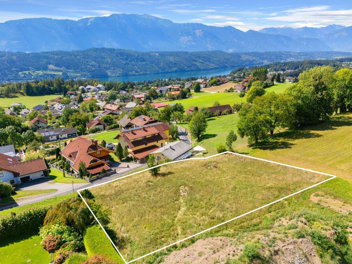 Nahaufnahme eines großen, umrandeten Grundstücks mit Blick auf den See und die umliegende Berglandschaft.