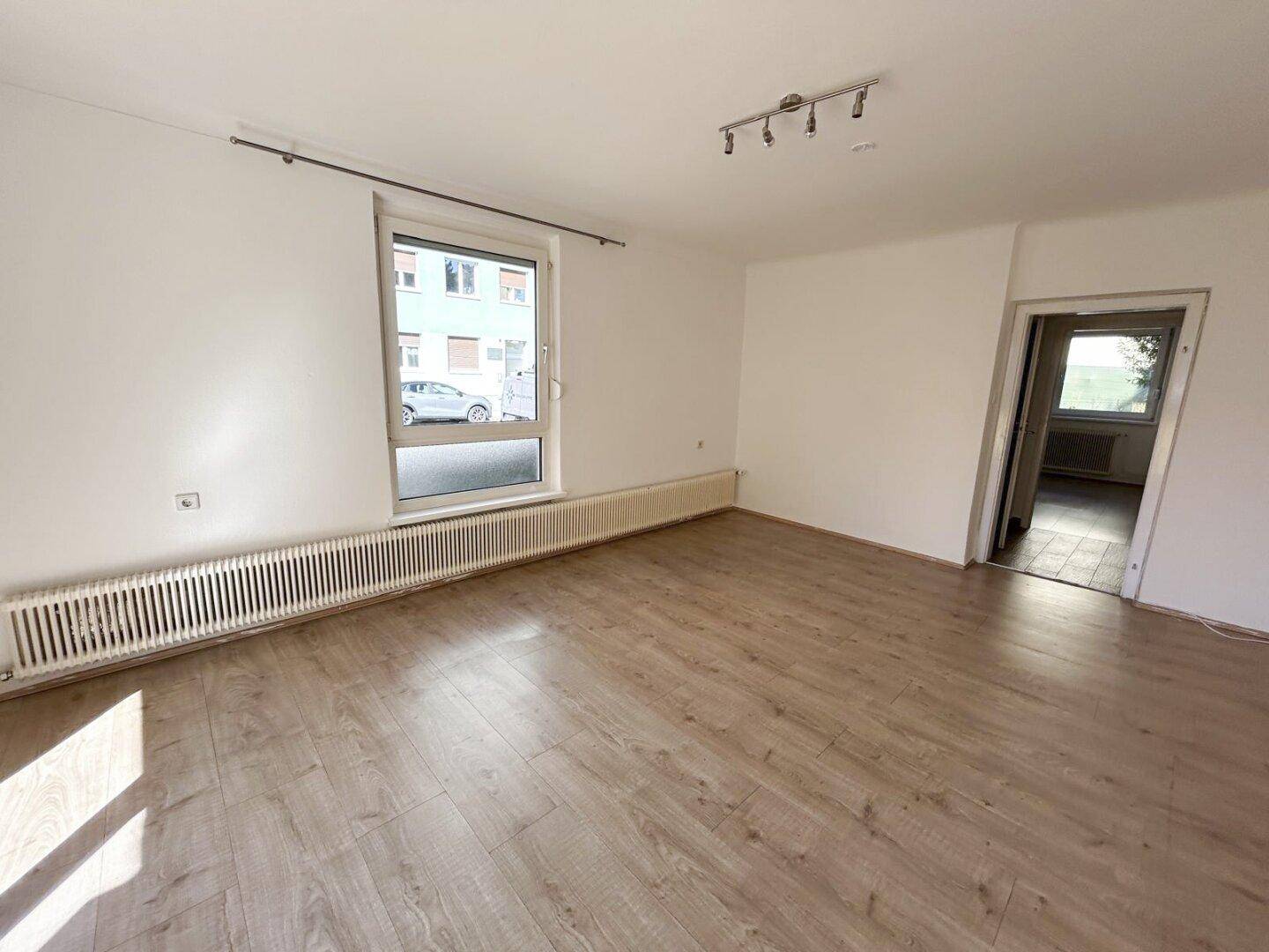 Geräumiges Zimmer mit Laminatboden und einem Fenster, das viel Tageslicht hereinlässt.