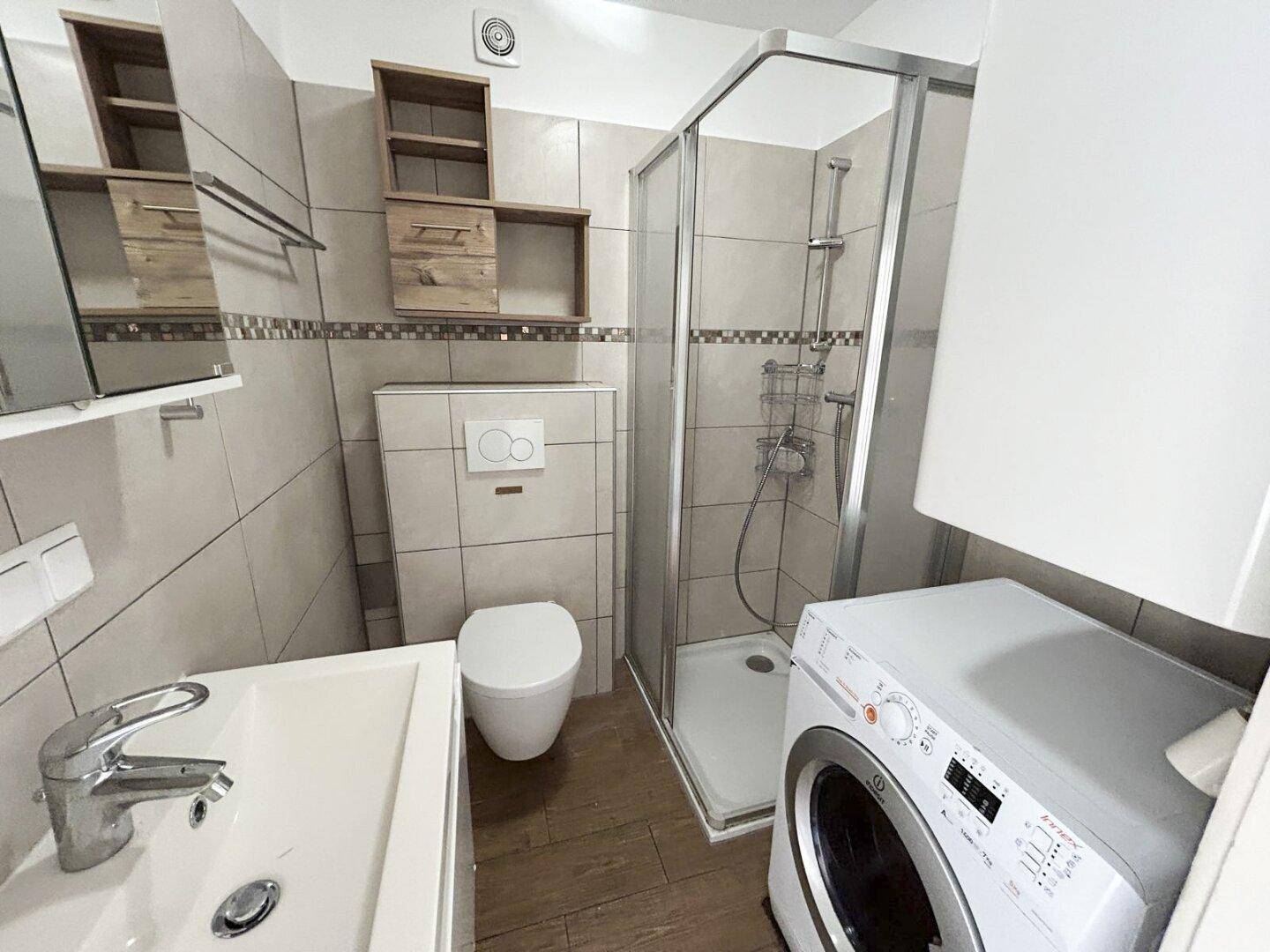 Funktionales Badezimmer mit Duschkabine, wandhängendem WC und Waschbecken.