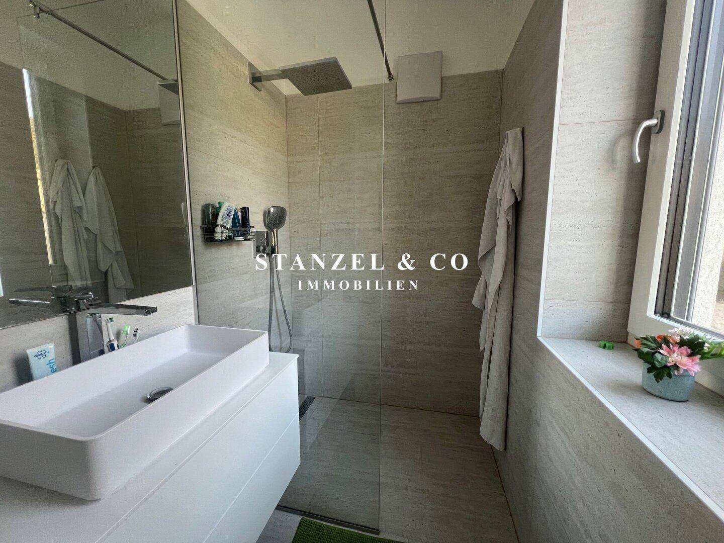 Modernes Badezimmer mit begehbarer Dusche und Waschtisch mit großem Spiegel.