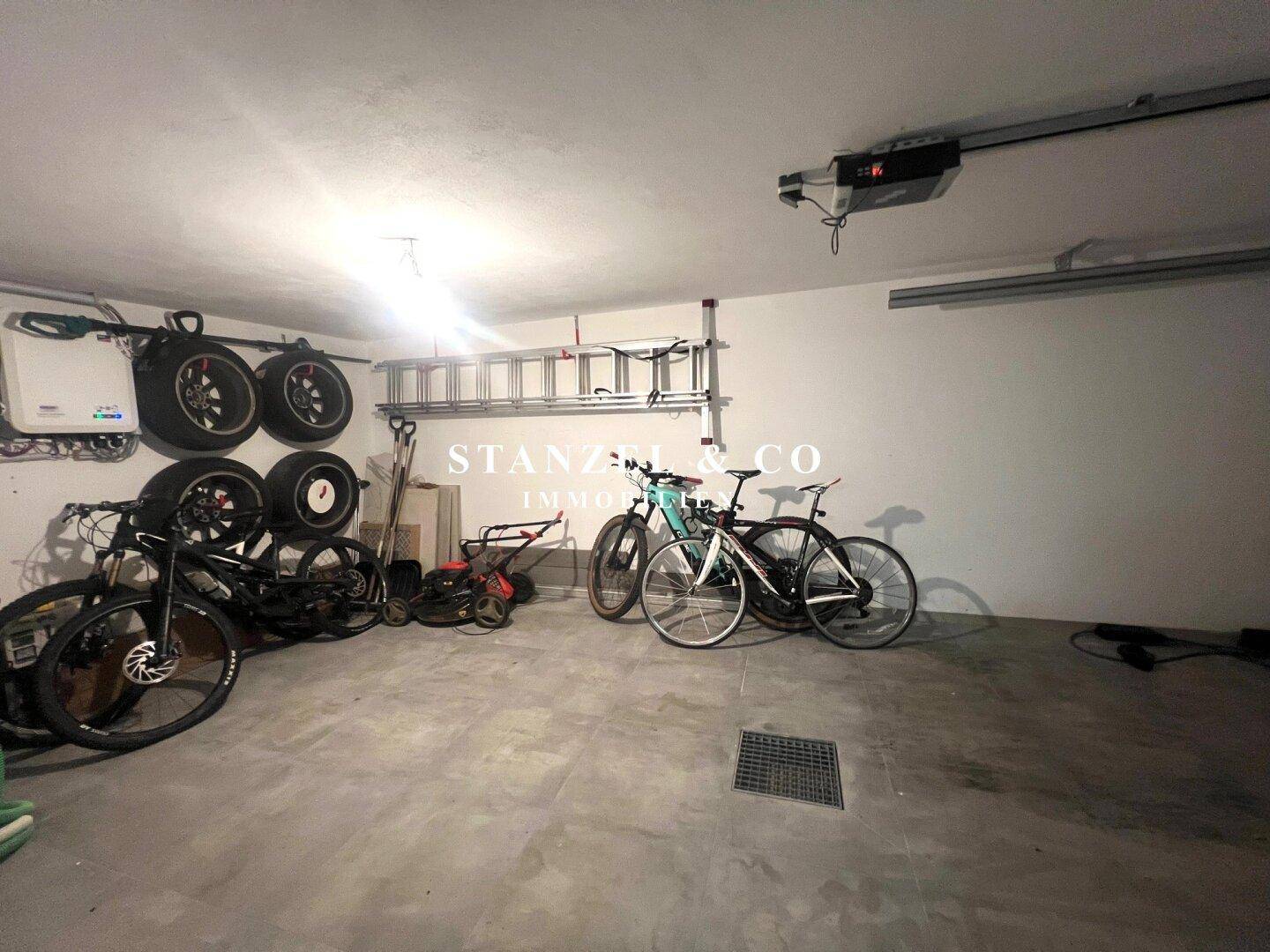 Geräumige Garage mit automatischem Tor und Platz für Fahrzeuge und Fahrräder.