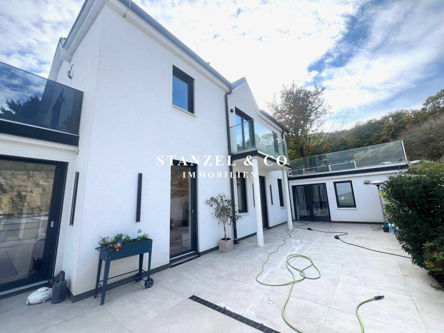 Moderne Villa mit weitläufiger Terrasse und Stufen, die zum Gartenbereich führen.