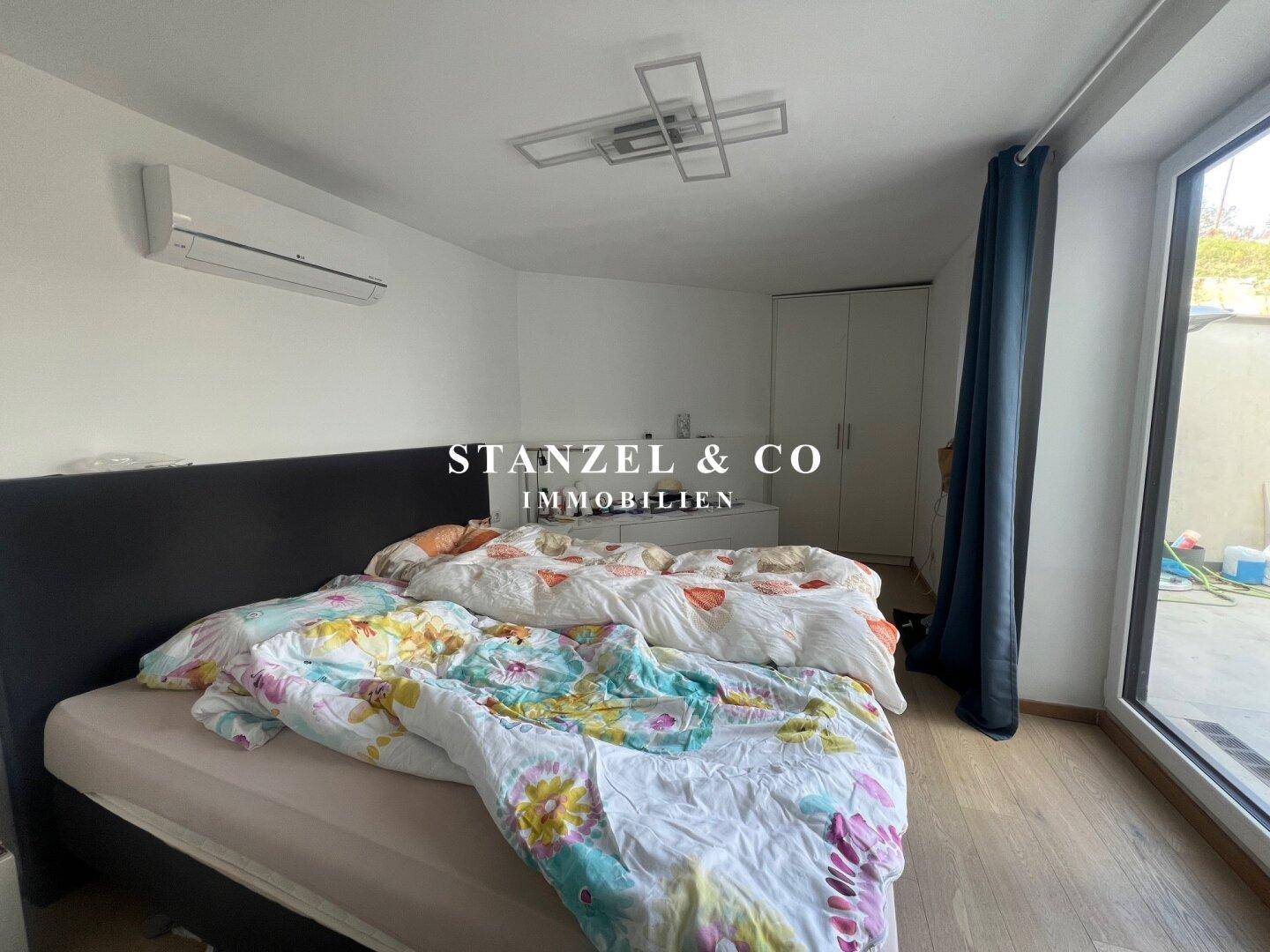 Helles Schlafzimmer mit Holzboden, großem Bett und Blick auf die Terrasse.